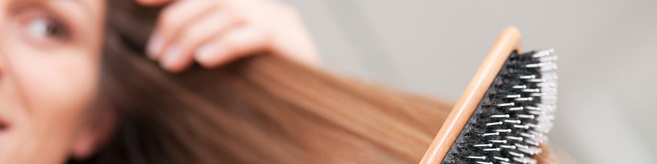 Mulher escovando os cabelos com escova de cerdas largas para ilustrar cuidados diários sobre como evitar caspa com uma rotina capilar adequada.