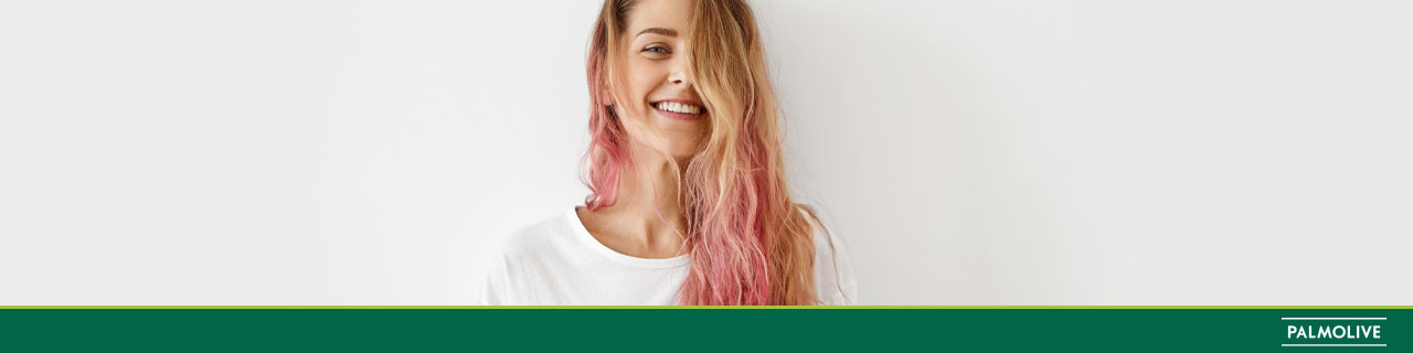 Mulher de cabelo colorido sorrindo e pensando em como fazer o cabelo crescer