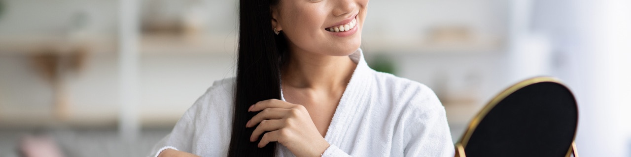 Mulher penteando seu cabelo alinhado depois de usar um shampoo anti-frizz