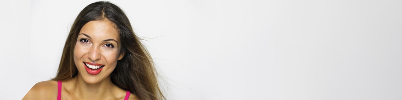 Mulher sorridente com fios visivelmente saudáveis porque usa um shampoo para cabelo liso