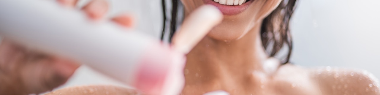 Mulher sorrindo ao tomar banho e aplicar um sabonete líquido cheiroso da Palmolive na esponja